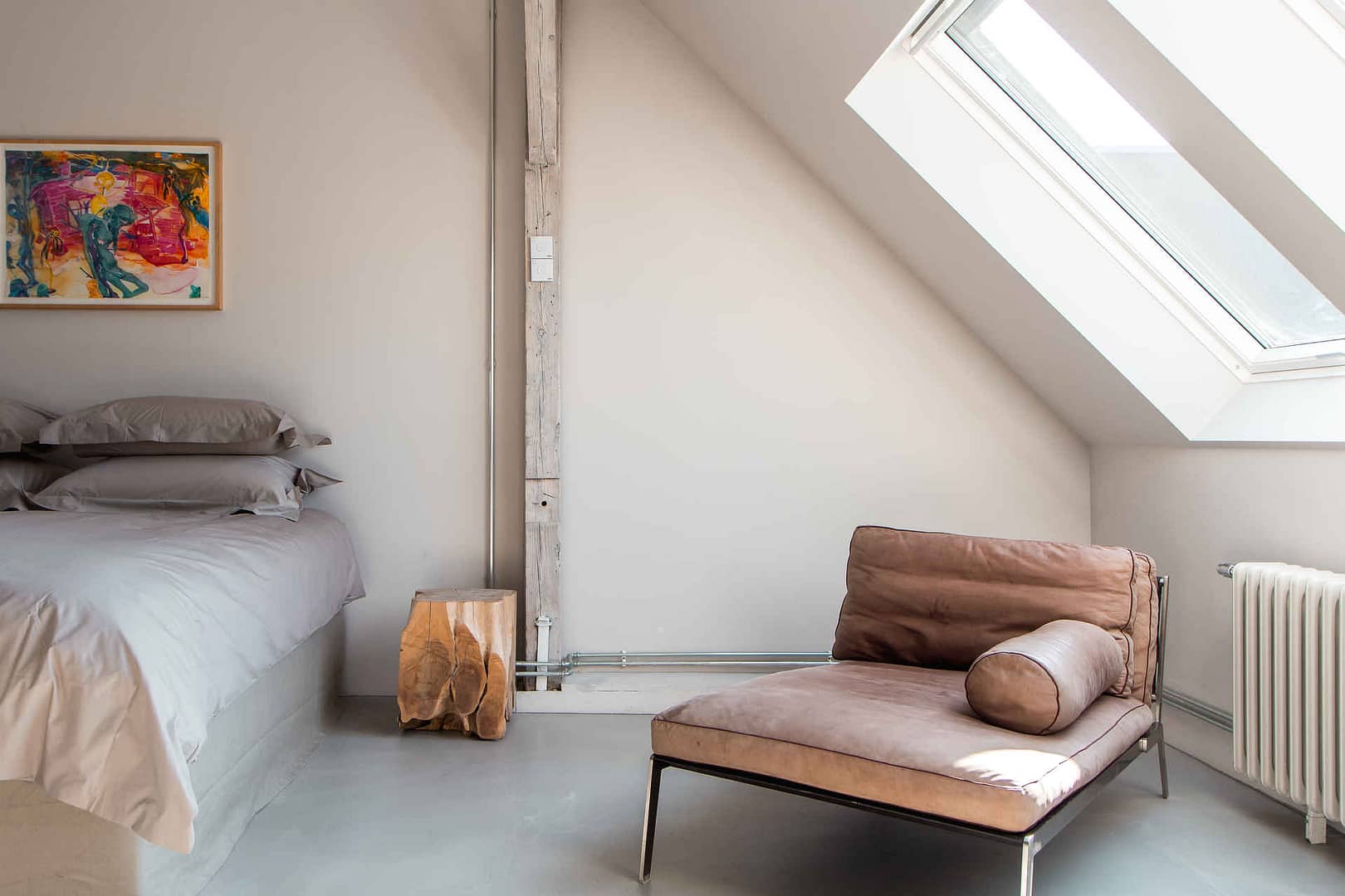 Schlafzimmer mit brauner Liege, Bett mit grauer Bettwäsche und Oberlicht