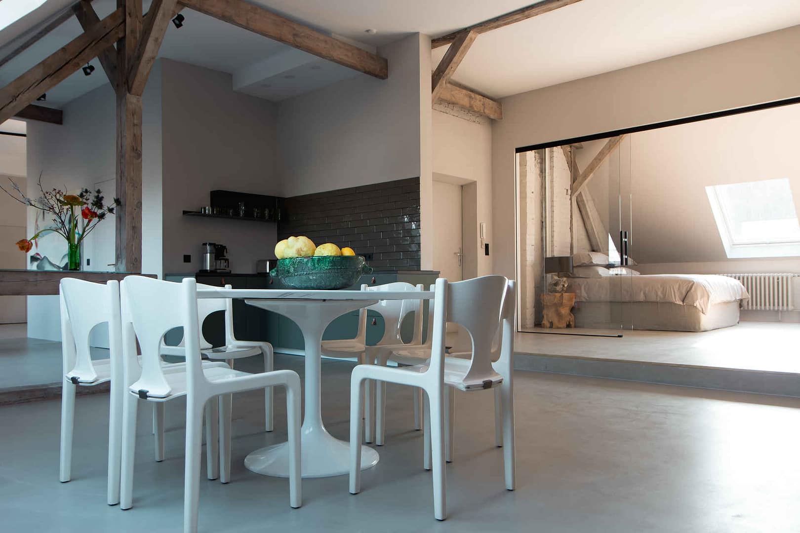 Essbereich mit Tulip Table, offener Küche und Blick ins Schlafzimmer