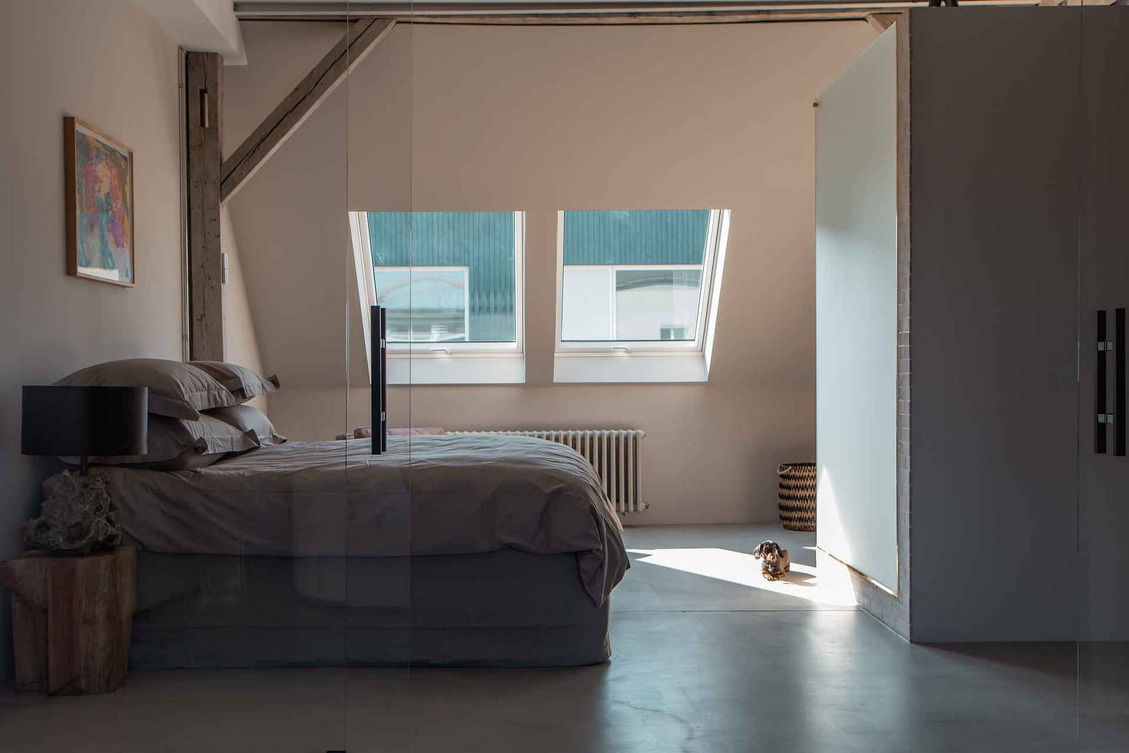 Schlafzimmer mit Dachfenstern, grauer Bettwäsche und Tageslicht im Studio unter dem Dach