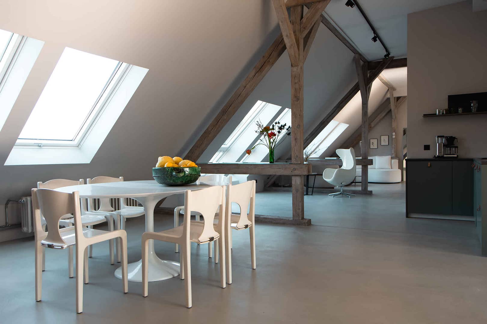 Essbereich mit weißen Designstühlen, Dachschrägen und Tageslicht im Dachgeschoss-Studio