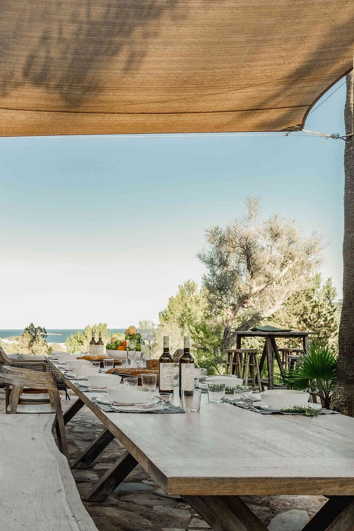 Außenbereich einer Finca mit Steinmauer, Sitzbereich mit hellen Polstern und Sonnensegel