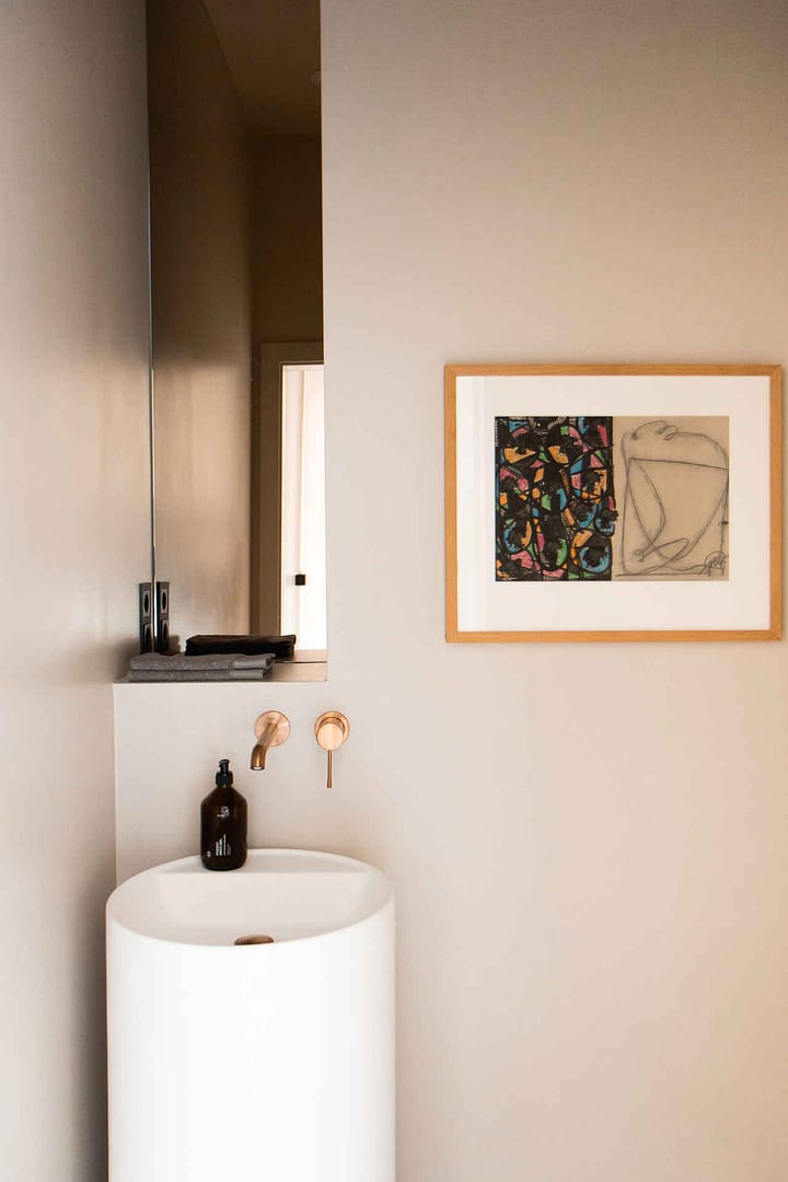 Design Studio Berlin – Gäste-WC mit freistehendem Waschbecken, messingfarbenen Armaturen und moderner Wandkunst