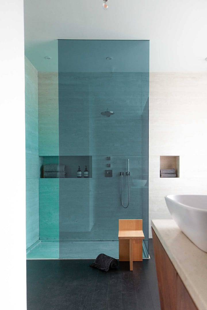 Design Apartment Berlin – bodengleiche Regendusche mit blauer Glaswand, Holzhocker und Nischenregal im Badezimmer