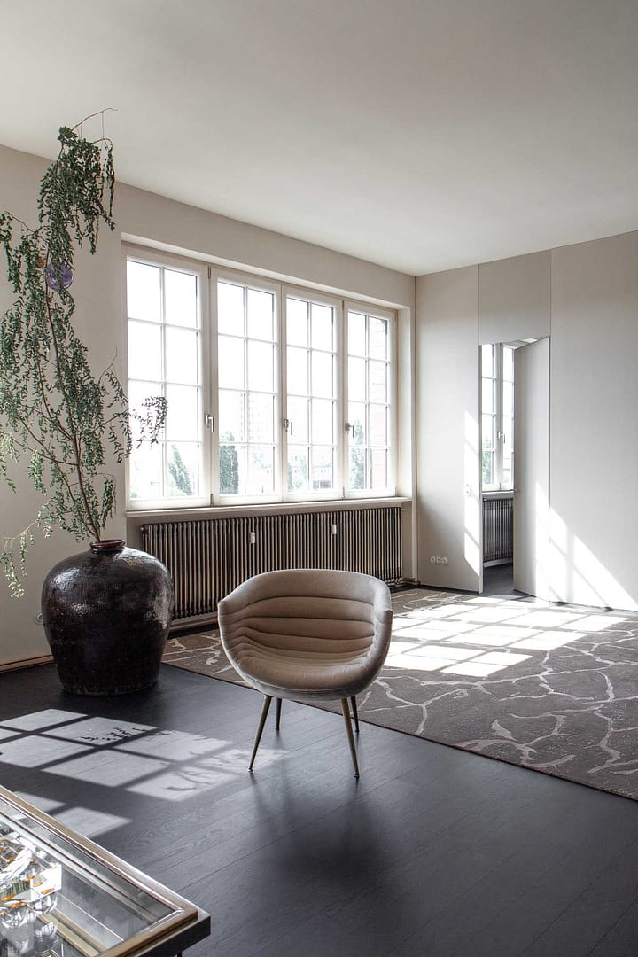 Design Apartment Berlin – Loungesessel vor großen Fenstern mit Tageslicht und Design-Teppich