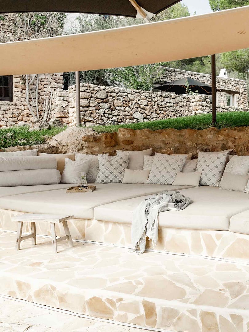 große, in Stein eingelassene Außenlounge mit Polstern und Kissen unter Sonnensegeln